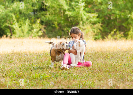 Ritratto di ragazza seduta su un terreno erboso insieme con i suoi animali domestici Foto Stock