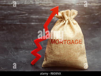 Una borsa con il denaro e l'iscrizione di ipoteca e freccia verso l'alto. Innalzamento dei tassi ipotecari e tasse. L'aumento degli oneri da interessi. Prestito per alloggiamento, apartm Foto Stock