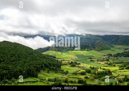 Una strada passato splendidi pascoli e due caldere vulcaniche in Sete Cidades, Sao Miguel. Foto Stock