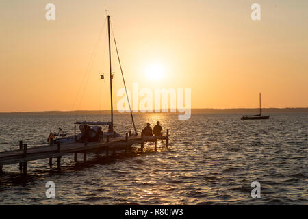 Jetty e storico barche a vela (Auswanderer) sul Lago Steinhude al tramonto. Bassa Sassonia, Germania Foto Stock