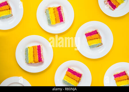 Luminoso modello di torta. Top Visualizza set di rainbow fette di torta su bianco piastre tonde su sfondo giallo. Happy bithday, parte il concetto di layout. Selective fo Foto Stock