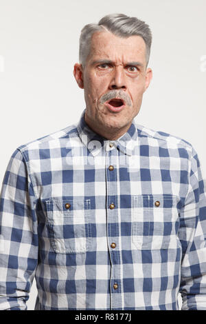 Ritratto di arrabbiato urlando vecchio uomo su grigio di sfondo per studio. Le emozioni umane concept Foto Stock
