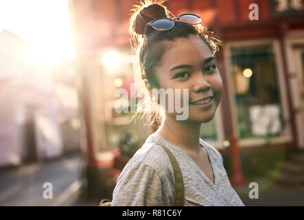 Sorridente giovane donna asiatica passeggiate in città Foto Stock