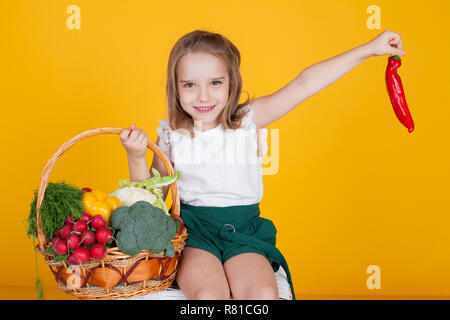 Bellissima ragazza con una cesta di verdure fresche, ravanelli, broccoli, pomodoro pepe Foto Stock