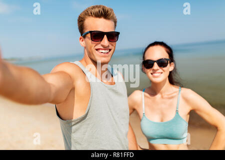 Giovane tenendo selfie tramite smartphone sulla spiaggia Foto Stock