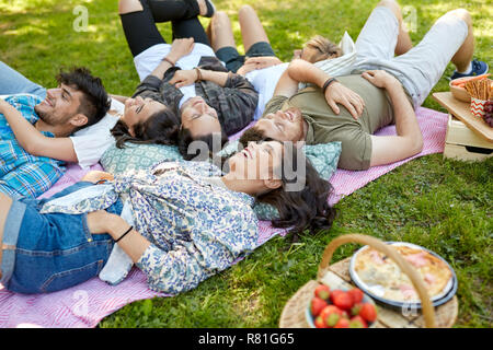 Happy amici agghiaccianti sulla coperta picnic in estate Foto Stock