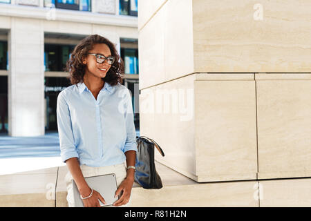 Donna sorridente indossando occhiali azienda tavoletta digitale Foto Stock