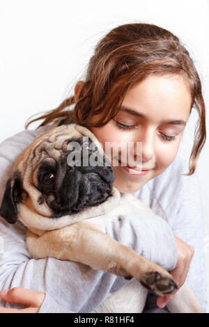 Felice piuttosto sorridente ragazza adolescente abbracciando carino pug dog con amore Foto Stock