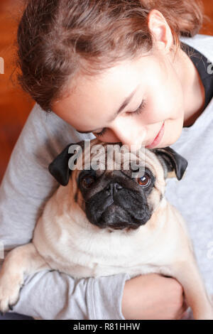 Felice piuttosto sorridente ragazza adolescente abbracciando carino pug dog con amore Foto Stock