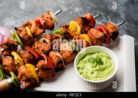 Pollo Tikka /Kebab sghemba. Tradizionale piatto indiano cucinati sul carbone e fiamma, condito & colorfully guarnita. servita con chutney di verde e insalata mista Foto Stock