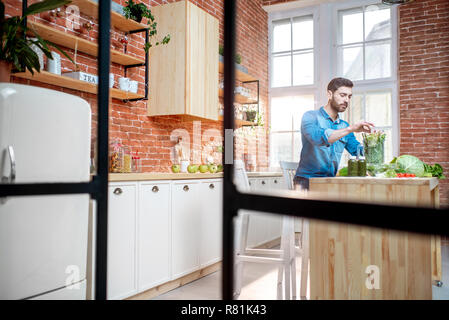 Uomo vegetariano con prodotti crudi sulla cucina, ampia vista interna sul bellissimo loft cucina Foto Stock