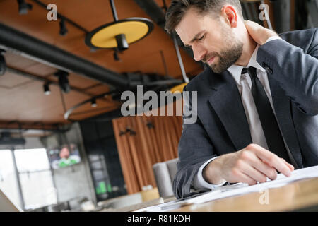 I mediatori di affari il pranzo al ristorante seduta toccando il collo dolore muscolare Foto Stock