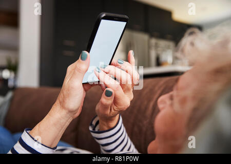Senior donna disteso sul lettino usando smartphone, close up Foto Stock