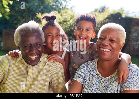 Senior coppia nero seduti all'aperto con i nipoti Foto Stock