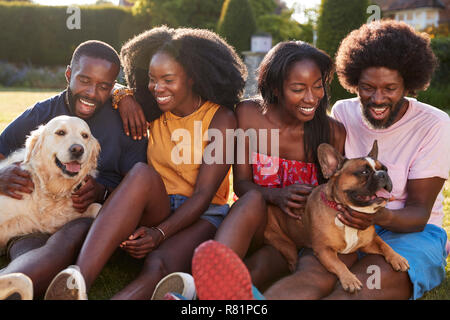 Due coppie con cani seduti in un giardino Foto Stock