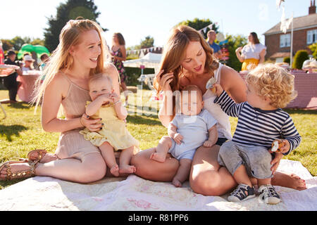 Due mamme con bambini sul tappeto a giardino estivo Fete Foto Stock