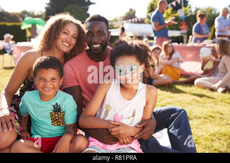 Ritratto di famiglia con bambini seduti sul tappeto a giardino estivo Fete Foto Stock