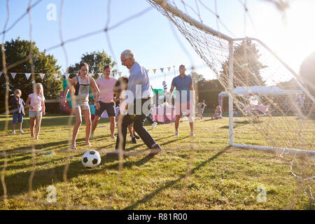 Bambini che giocano una partita di calcio con il Padre e il nonno in giardino estivo Fete Foto Stock