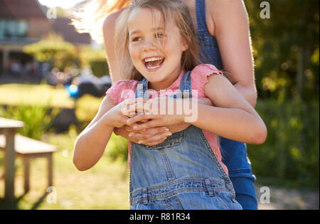Chiudere fino alla madre il gioco di oscillazione e la figlia in giro in giardino d'estate Pub Foto Stock