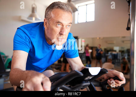 Senior uomo esercita sulla macchina in bicicletta in palestra Foto Stock