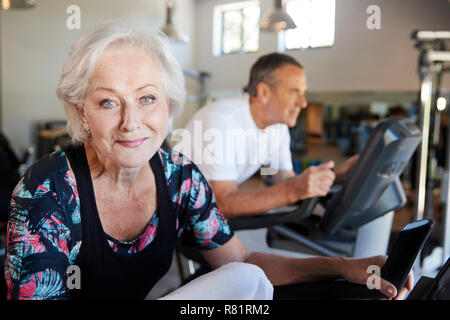 Ritratto di Active Senior donna riposo dopo che esercitano sul ciclismo macchine In Palestra Foto Stock