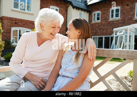 La nipote seduta sul banco di lavoro con la Nonna durante la visita alla casa di riposo Foto Stock