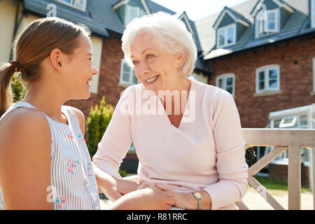 La nipote seduta sul banco di lavoro con la Nonna durante la visita alla casa di riposo Foto Stock