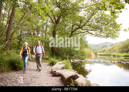 Coppia senior escursionismo lungo il percorso dal fiume in UK Lake District Foto Stock