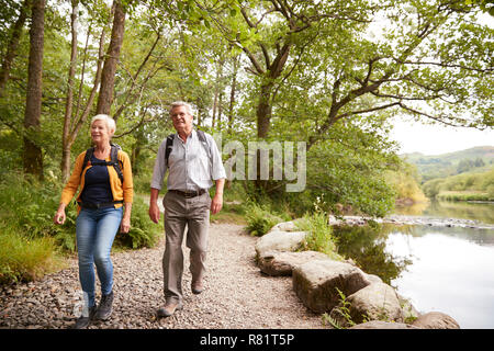 Coppia senior escursionismo lungo il percorso dal fiume in UK Lake District Foto Stock