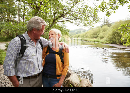 Coppia senior escursionismo lungo il percorso dal fiume in UK Lake District Foto Stock