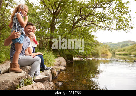 La famiglia sul camminare guardando fuori oltre il fiume in UK Lake District Foto Stock