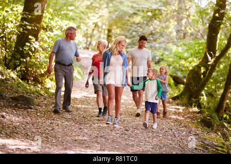 Generazione Multi Family godendo a piedi lungo il sentiero del bosco insieme Foto Stock
