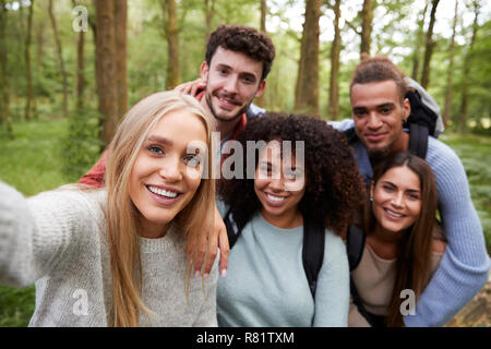 Multi etnico gruppo di cinque giovani amici adulti prendendo un selfie in una foresta durante un'escursione, ritratto Foto Stock