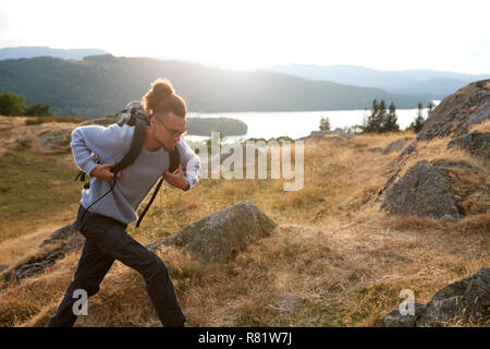 Un giovane razza mista uomo correre tutto solo in montagna Foto Stock