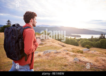 Un giovane adulto uomo caucasico camminare da solo su una collina, ammirando la vista, Vista laterale Foto Stock