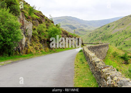 Una strada fiancheggiata con un muro di pietra nelle colline di pennini Foto Stock