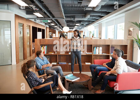 Casualmente vestito imprenditori e imprenditrici avente una riunione informale in un ufficio moderno Foto Stock