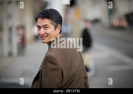 Ritratto di un imprenditore maturo guardando sopra la sua spalla mentre passeggiando per la città. Foto Stock