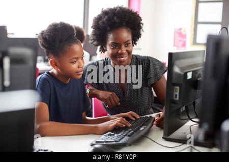 Insegnante aiutando femmina di alta scuola studente lavora a schermo in Classe Computer Foto Stock
