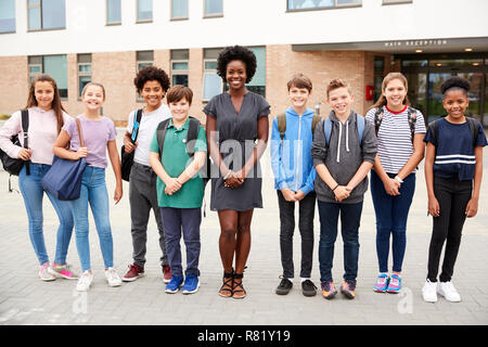 Ritratto di sorridere studente di scuola superiore gruppo con insegnante femminile in piedi al di fuori degli edifici scolastici