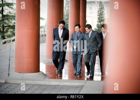 Quattro uomini d'affari avente una discussione mentre si cammina insieme all'esterno. Foto Stock