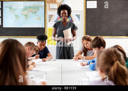 Ritratto di donna Insegnante di scuola superiore in piedi dalla tabella con gli studenti nella lezione Foto Stock