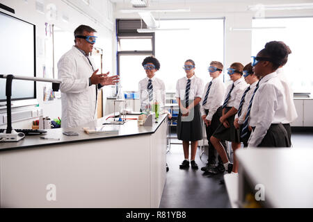 Maschio della High School Tutor insegnamento di alta scuola gli studenti indossano uniformi nella Classe di Scienze Foto Stock