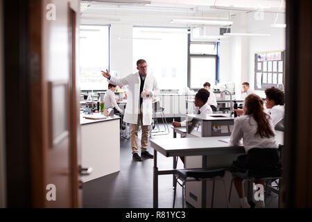 Maschio della High School Tutor insegnamento di alta scuola gli studenti indossano uniformi nella Classe di Scienze Foto Stock