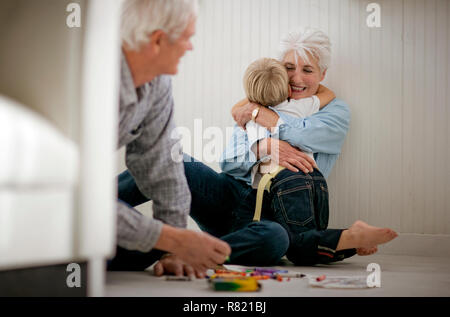 Il Toddler giocando e abbracciando i suoi nonni. Foto Stock