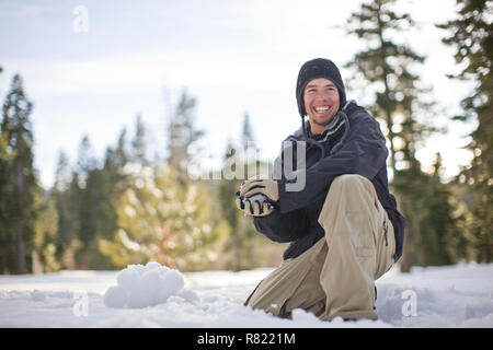 Giovane uomo si prepara a lanciare una palla di neve Foto Stock