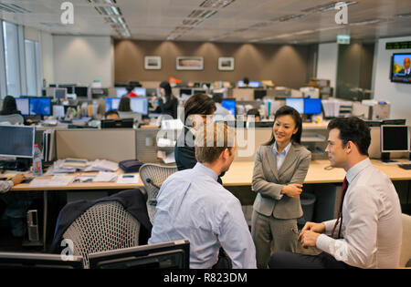 Un gruppo di imprenditori a discutere di lavoro in un ufficio affollato. Foto Stock