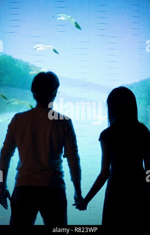Paio di guardare uno schermo tenendo le mani. Foto Stock