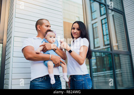 Coppia sposata, aman holding bambino donna uomo di contenimento sulle sue spalle. sullo sfondo Palazzo di vetro Foto Stock