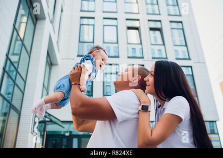 Coppia sposata, aman holding bambino donna uomo di contenimento sulle sue spalle. sullo sfondo Palazzo di vetro Foto Stock